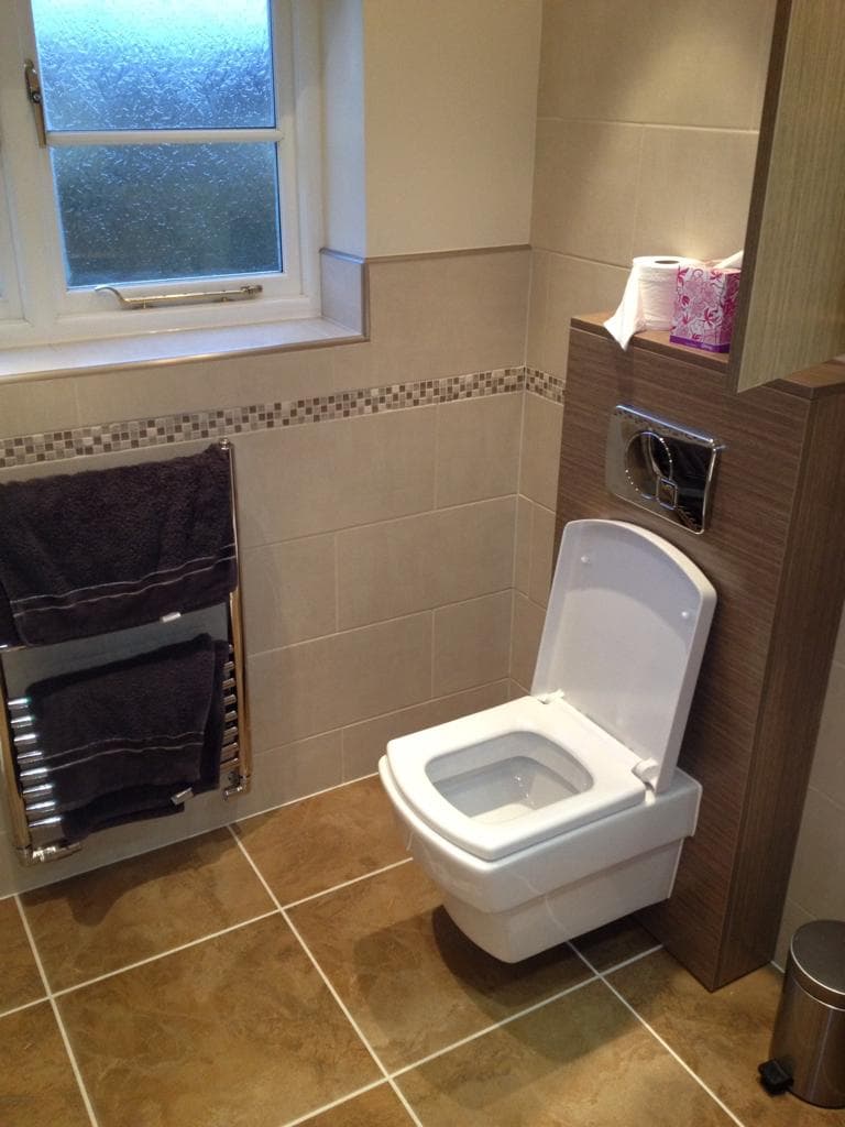 Tiled bathroom with wall-hung toilet and chrome heated towel rail
