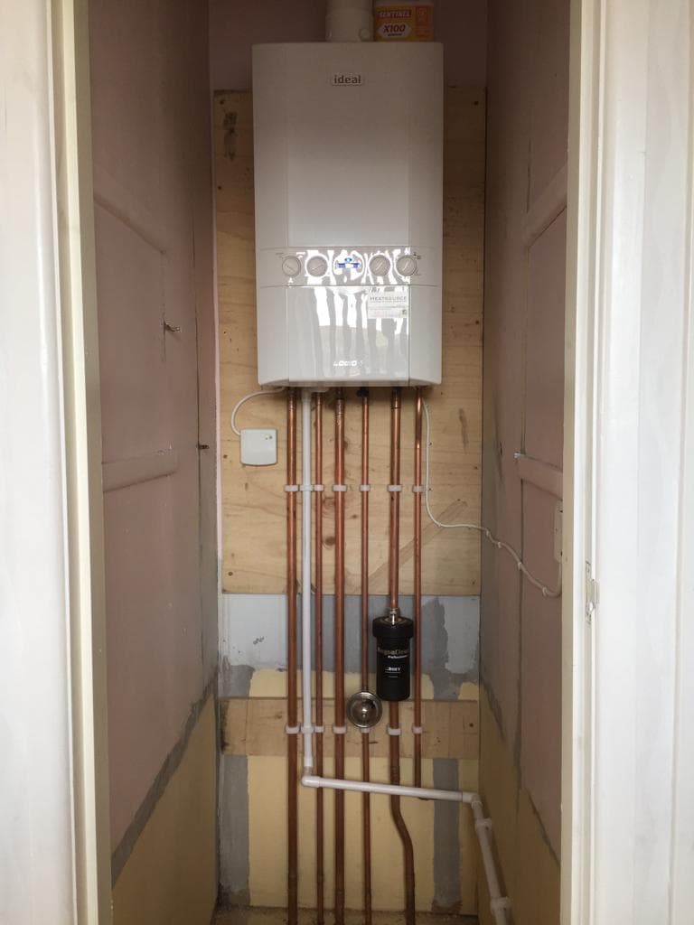 New wall-mounted boiler fitted in a cupboard with copper pipework below