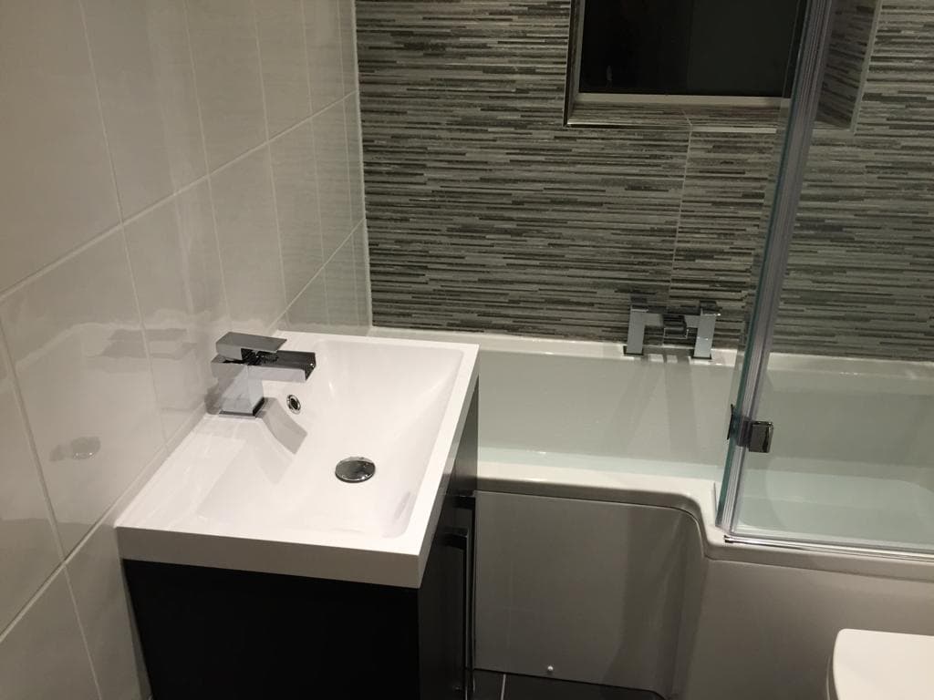 Bathroom with vanity basin and L-shaped shower bath